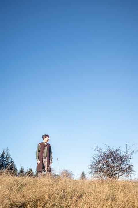 David Hughes, storyteller, standing in a wild grassy field at dusk